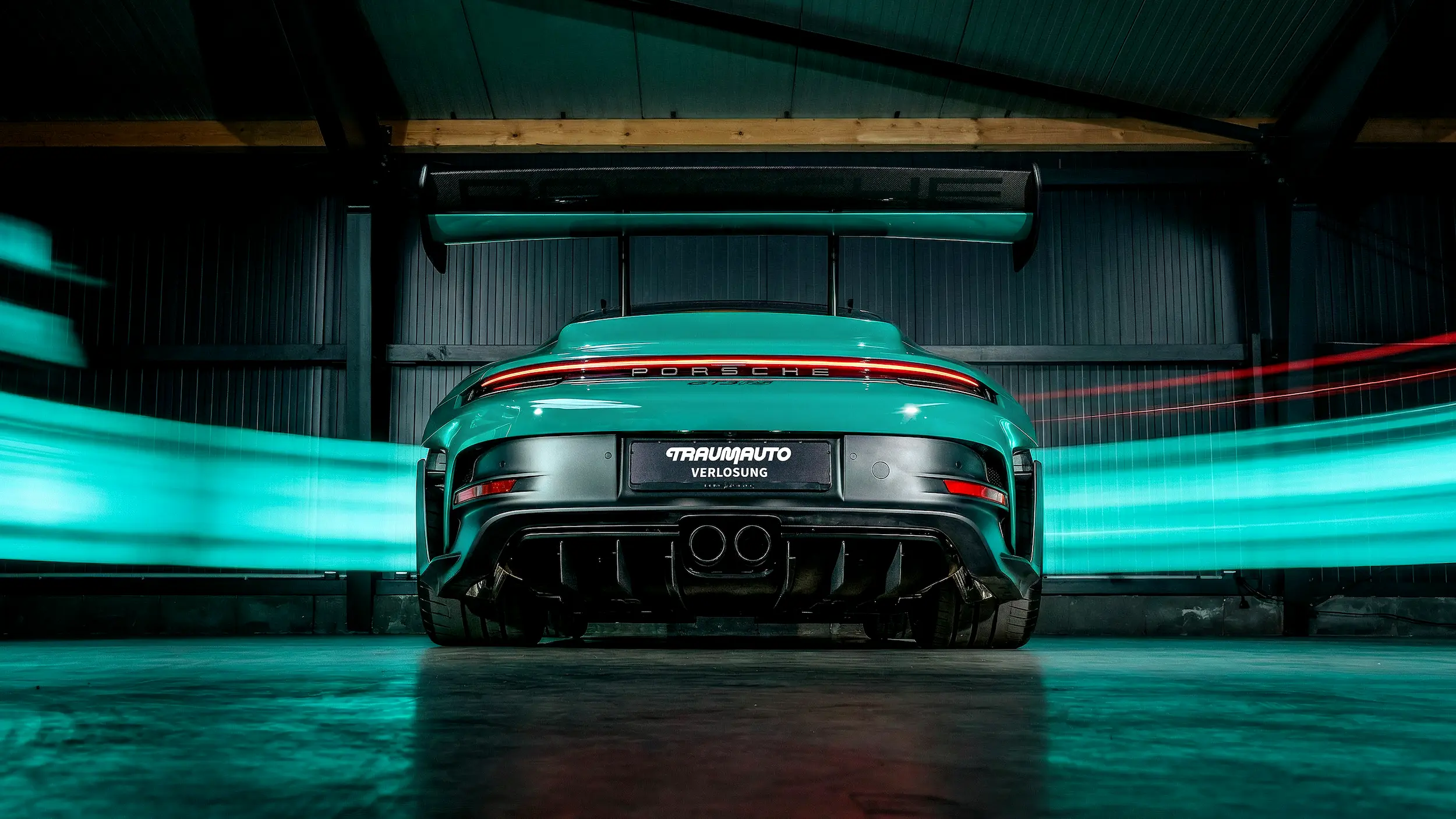 Heckansicht des Porsche 911 GT3 RS in Smyrna Green mit durchgehendem Rücklicht und dynamischen Lichtspuren in einer dunklen Halle