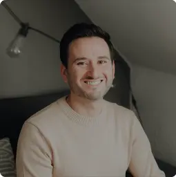 Porträt von Josué, lächelnd in Innenraum mit neutralem Hintergrund